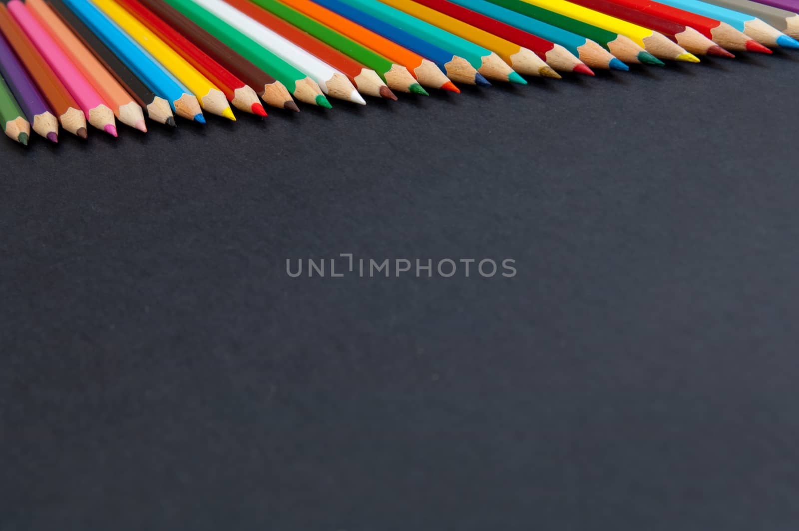 Pattern of color pencils isolated on black background close up