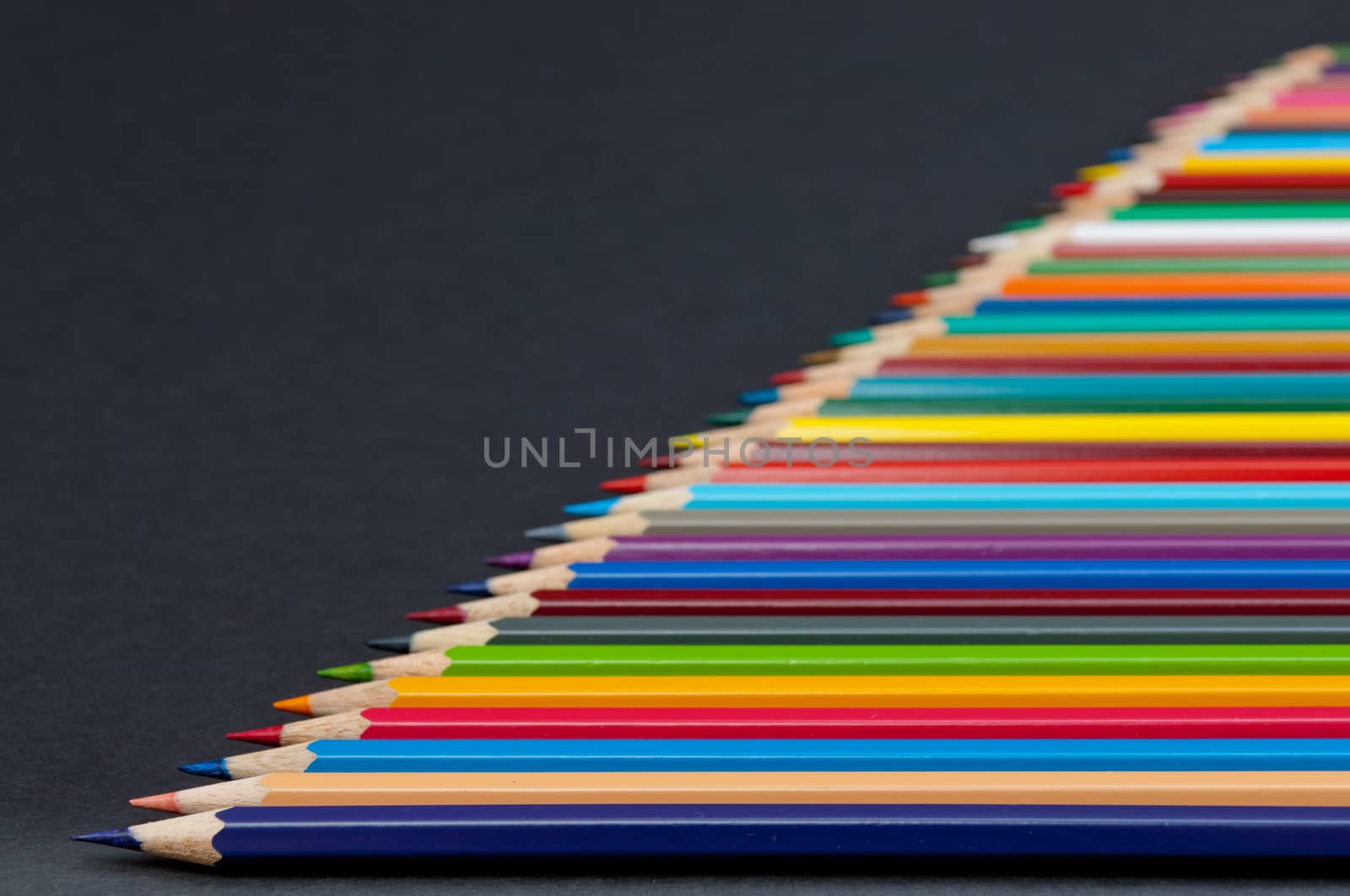 Pattern of color pencils isolated on black background close up