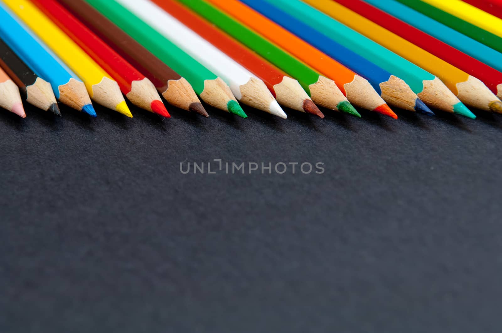 Pattern of color pencils isolated on black background close up