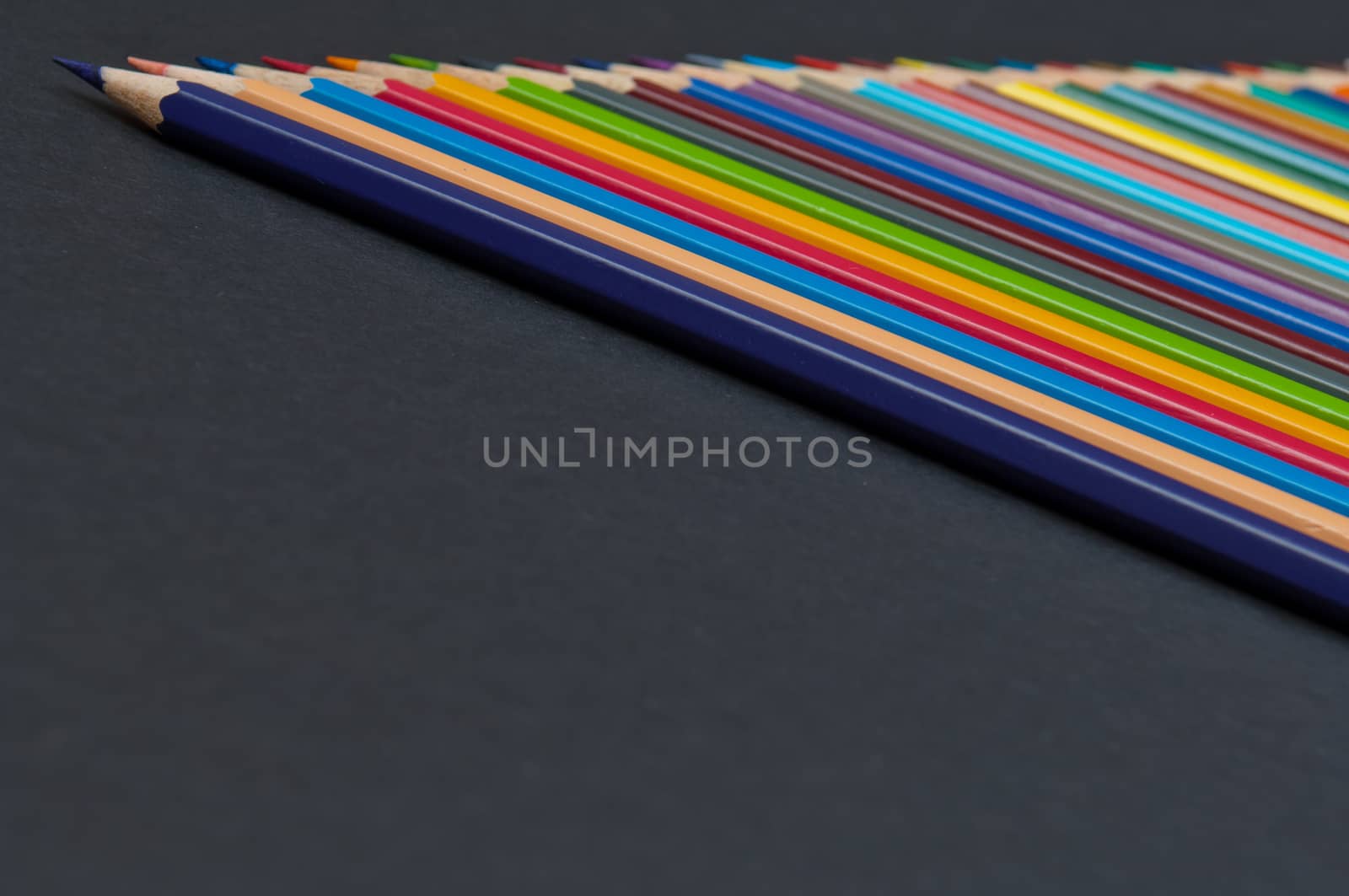 Pattern of color pencils isolated on black background close up