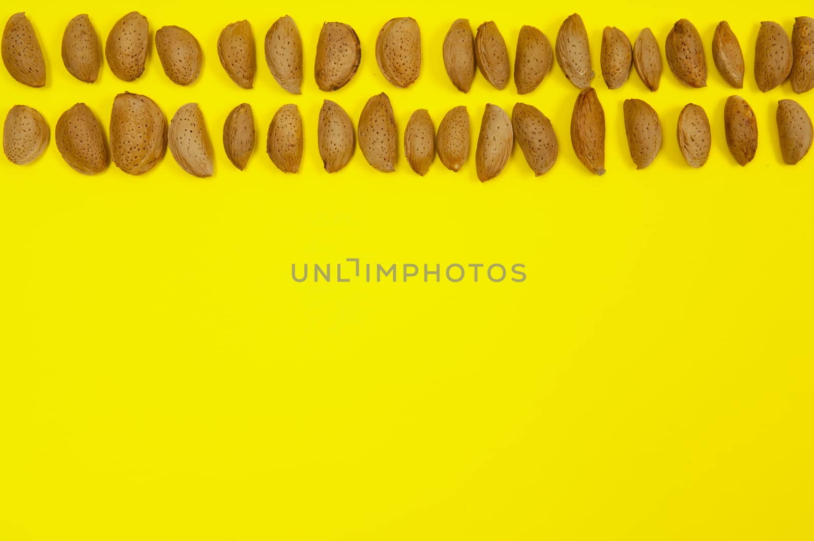 In shell raw almonds on yellow background with copy space