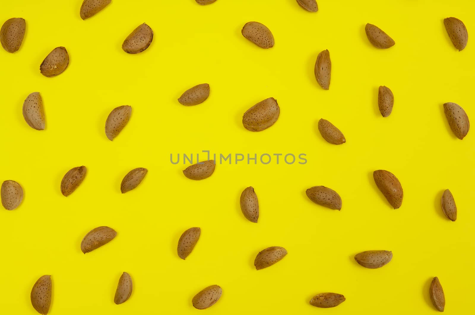 In shell raw almond on yellow background
