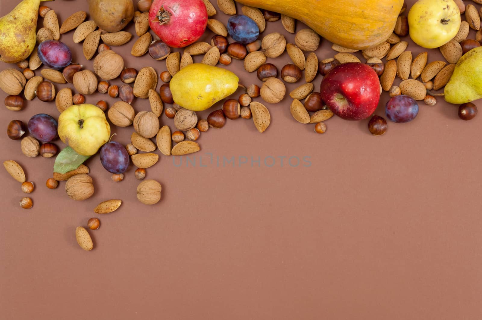 Organic autumn fruits and nuts on brown background with copy space