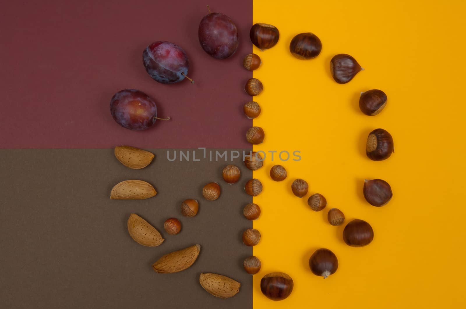 Peace symbol of in shell nuts and autumn fruits on split background