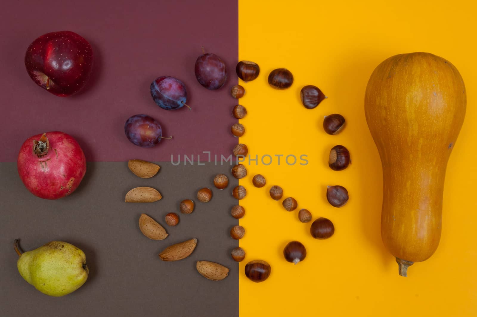Peace symbol of in shell nuts and autumn fruits on split background