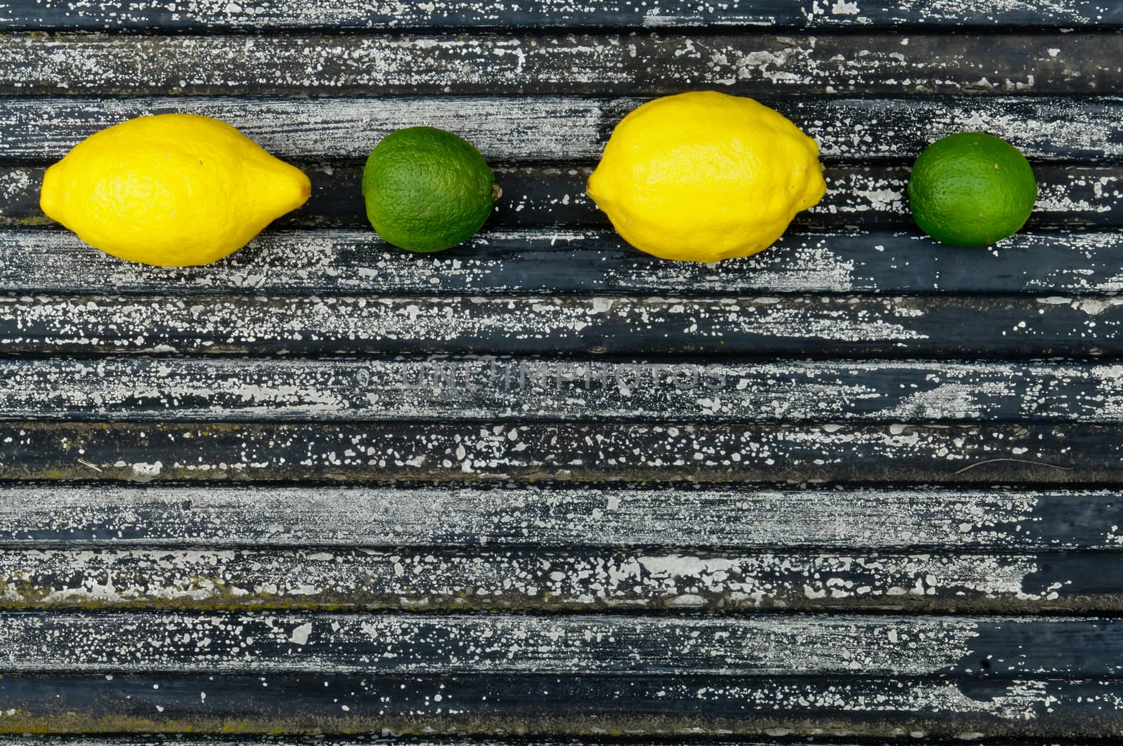 Lemon and lime arrangement on old black textured metal surface