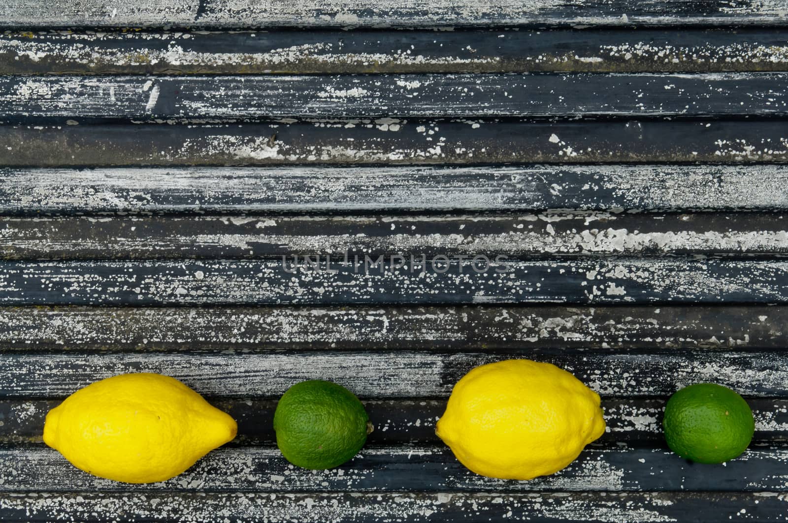 Lemon and lime arrangement on old black textured metal surface