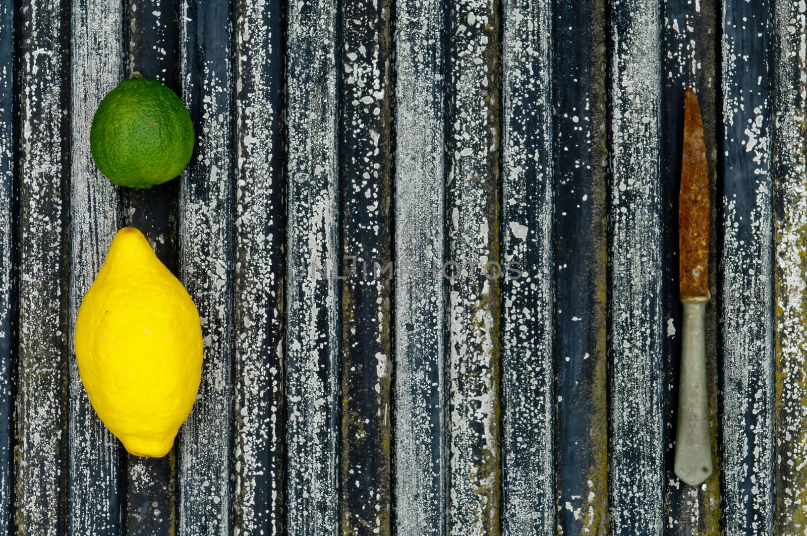 Lemon and lime arrangement on old black textured metal surface