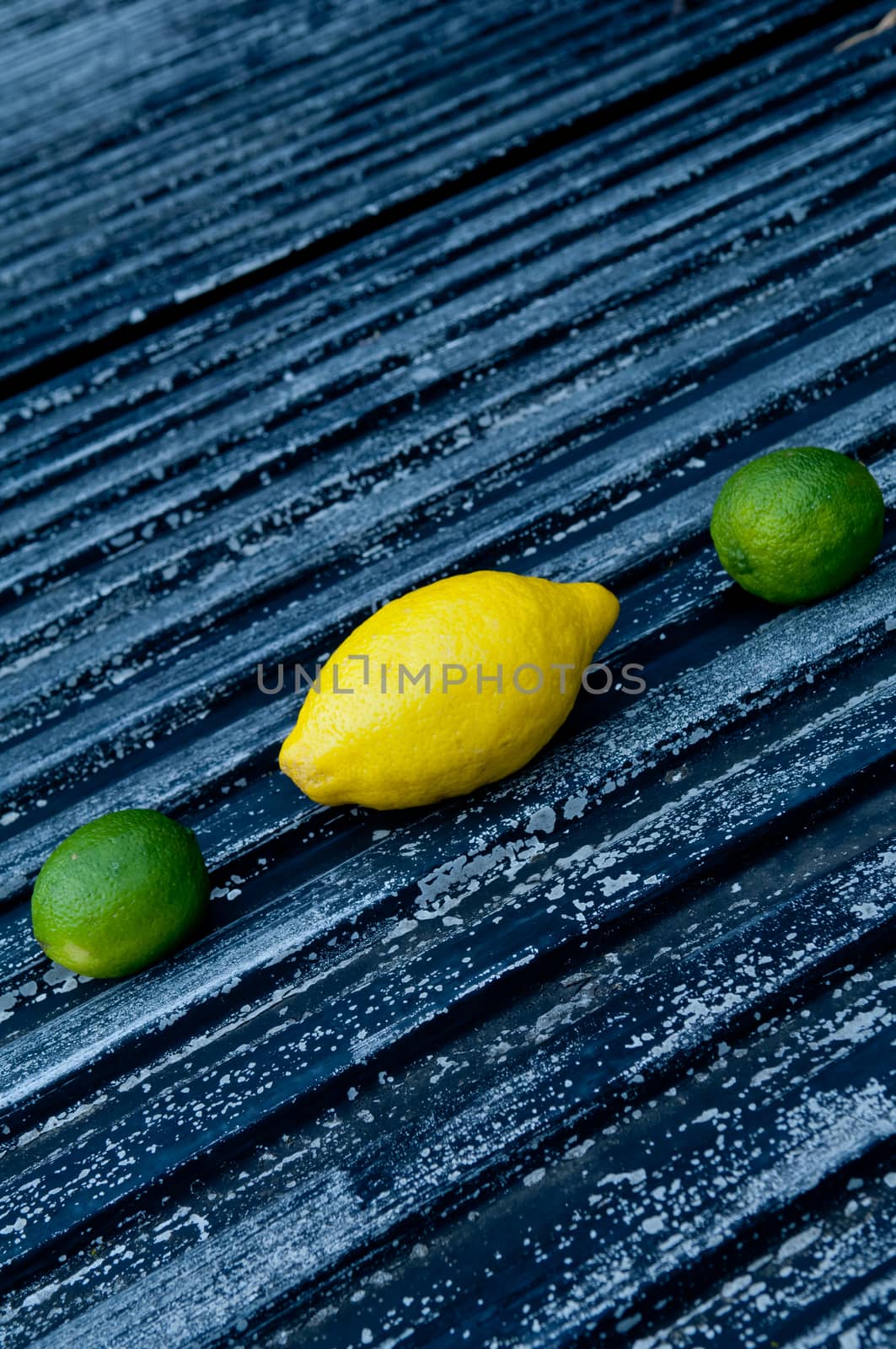 Lemon and lime arrangement on old black textured metal surface