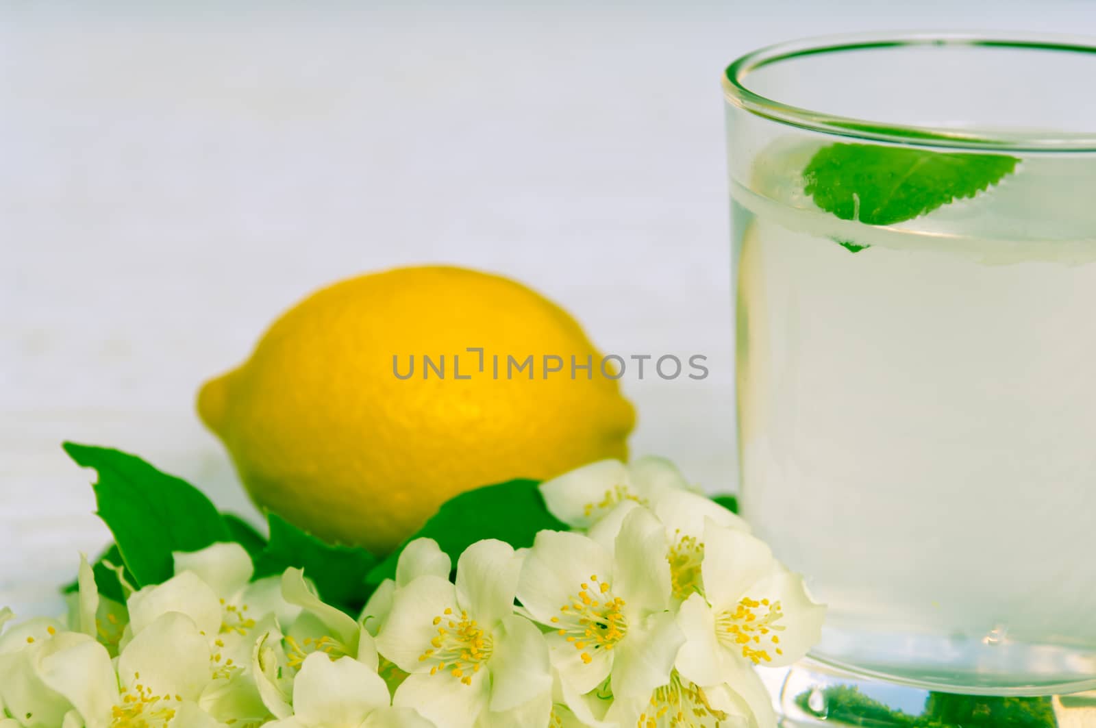 Lemonade with fresh lemon and mint leaves with copy space white flowers decoration