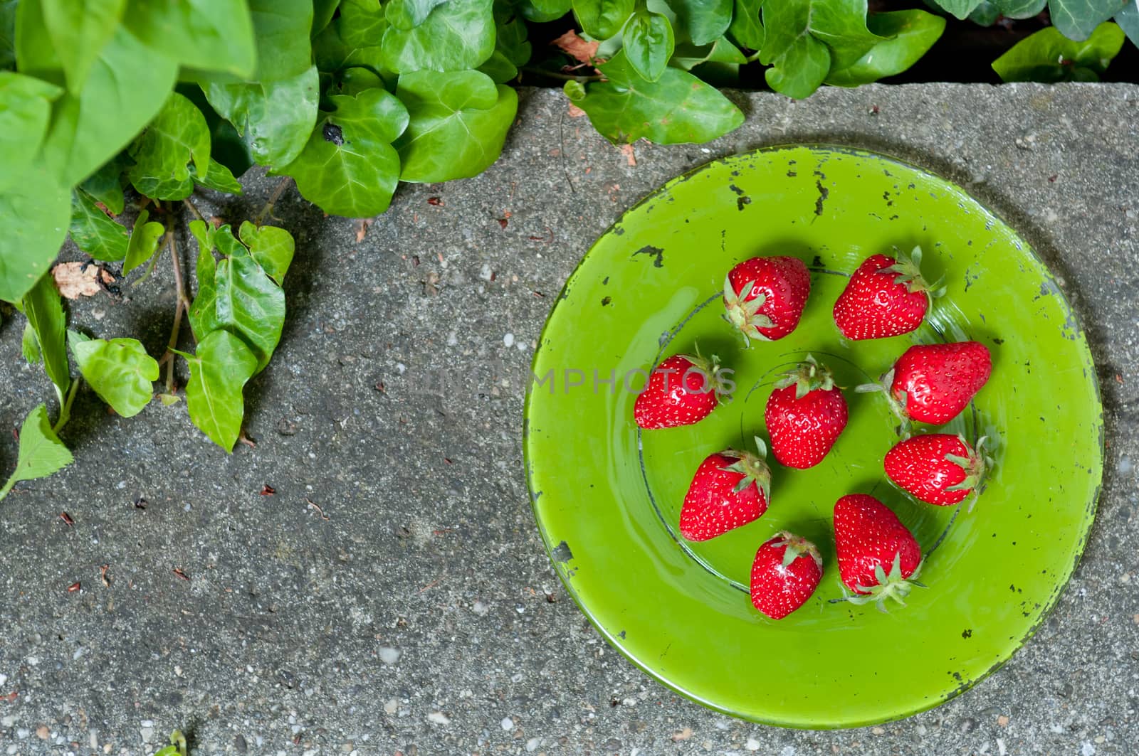 Delicious ripe strawberry  on green plate on grey stone flat lay Healthy fruit eating Top view
