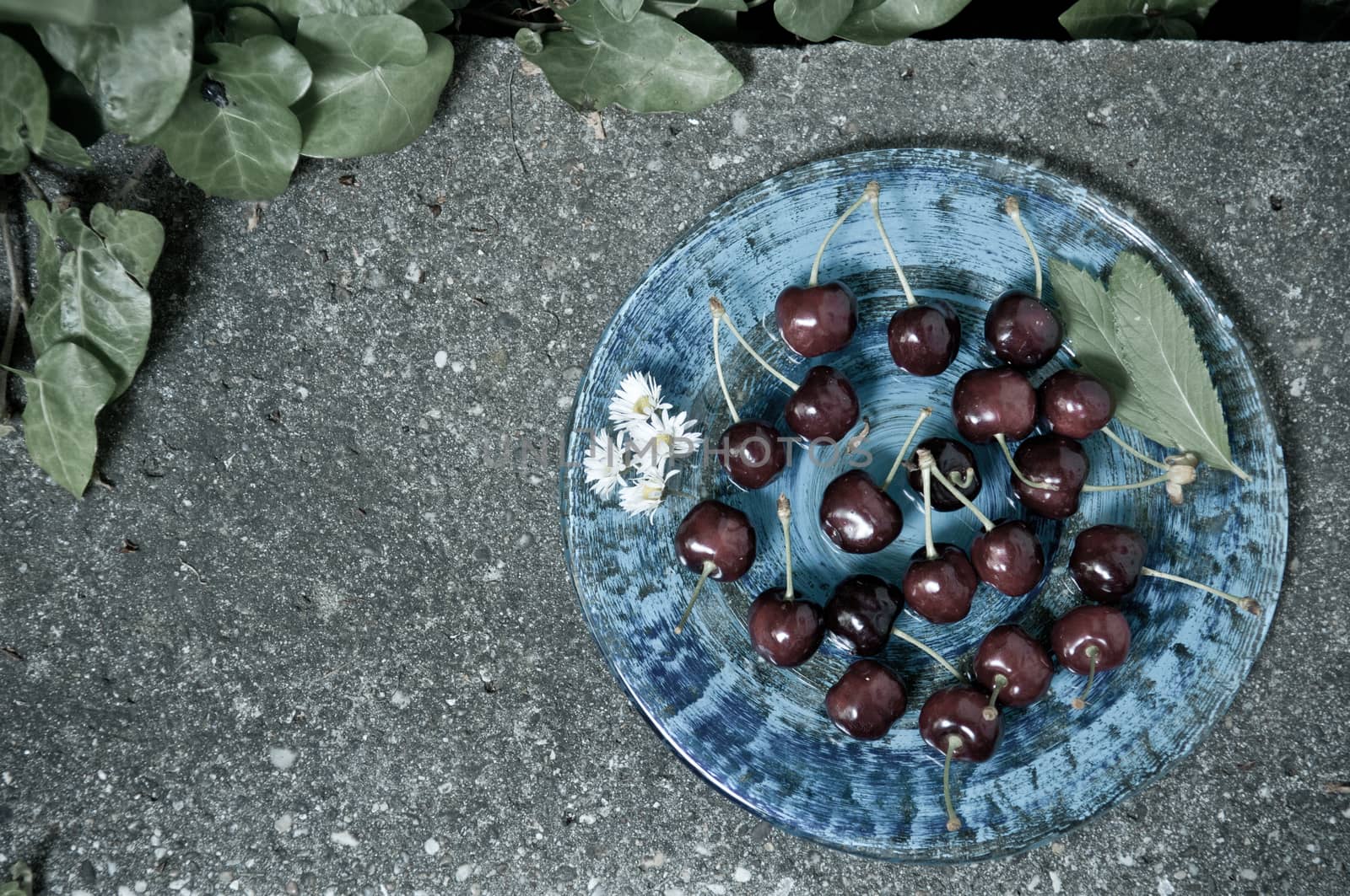 Delicious ripe cherry  on blue plate on grey stone flat lay Healthy fruit eating Top view
