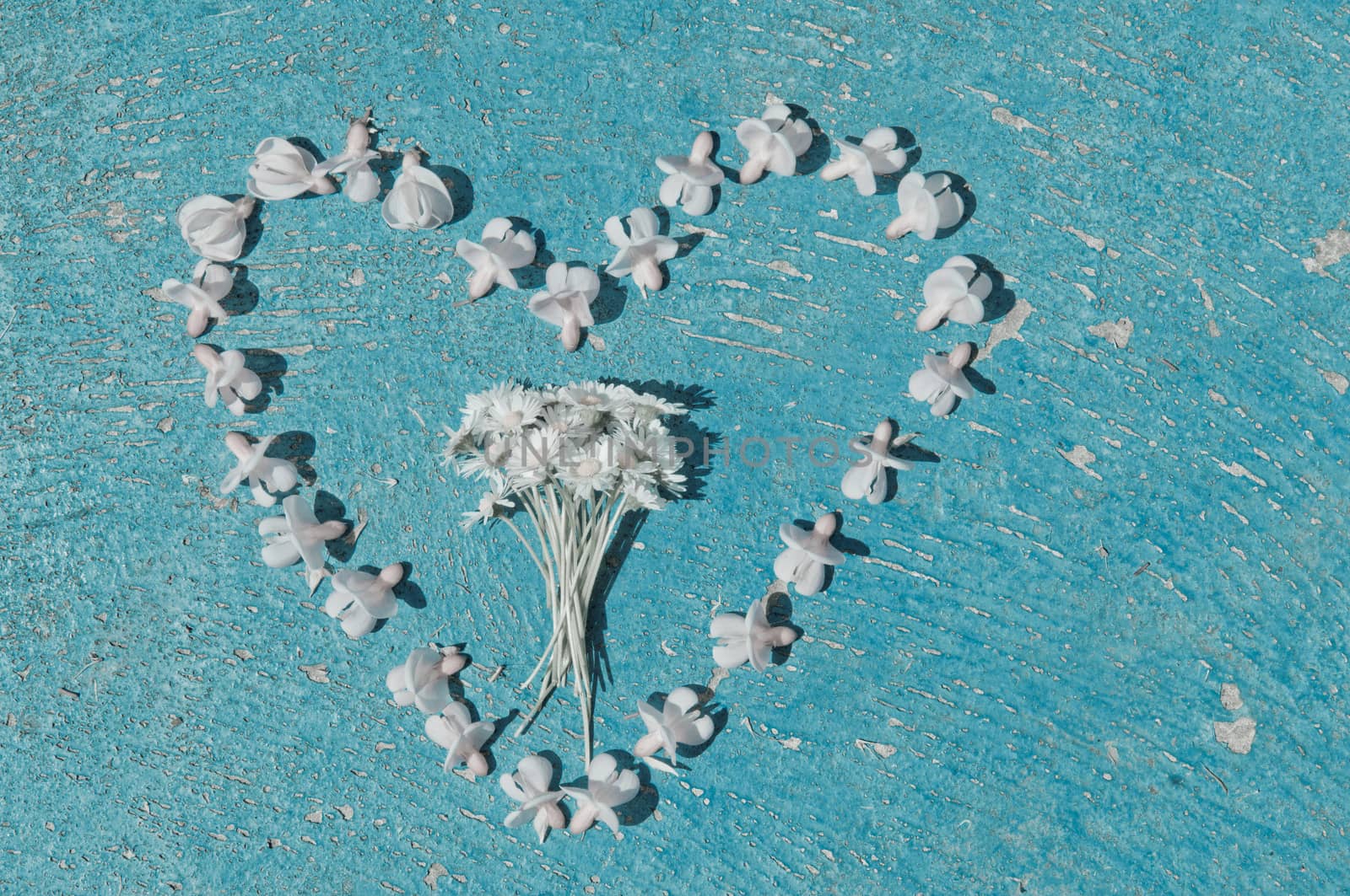 Heart shape formed from bleached flowers on an old texture light blue background  turquoise background vintage