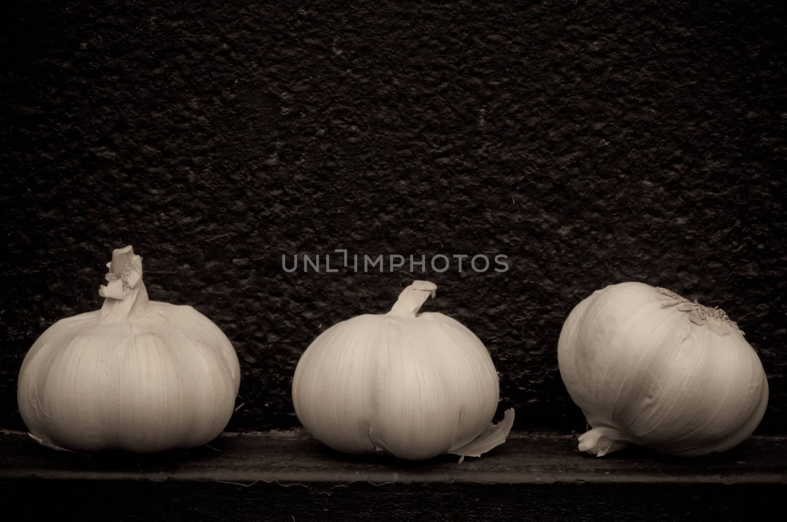 Garlic in front of rough textured black background metal background
