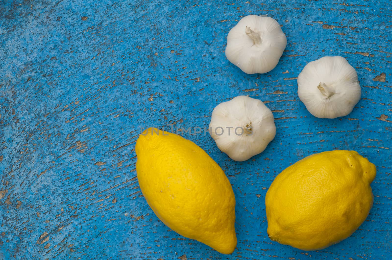 Old light blue textured background with lemon and   garlic turquoise background scratched surface