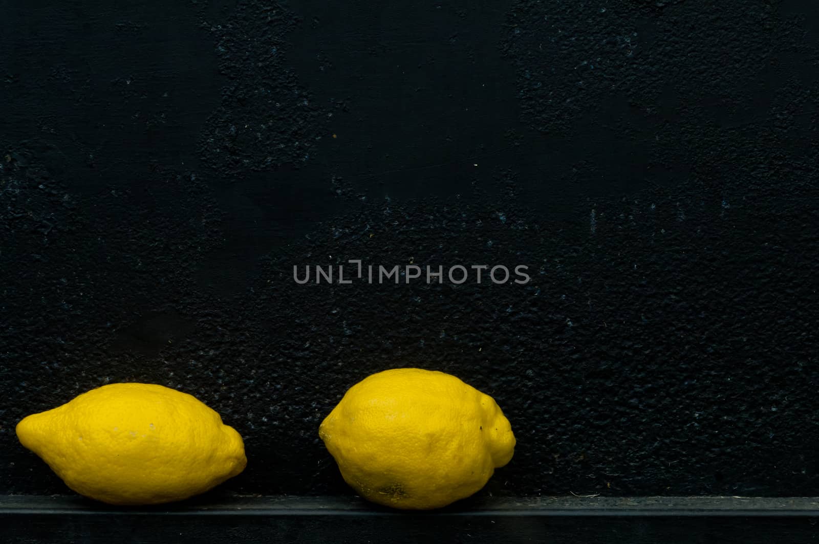 Lemon in front of rough textured black background metal background