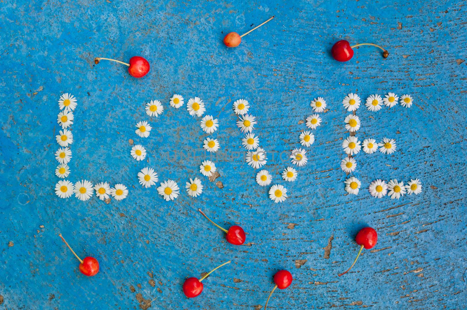 The word Love written of daisy flowers on textured blue background, top view