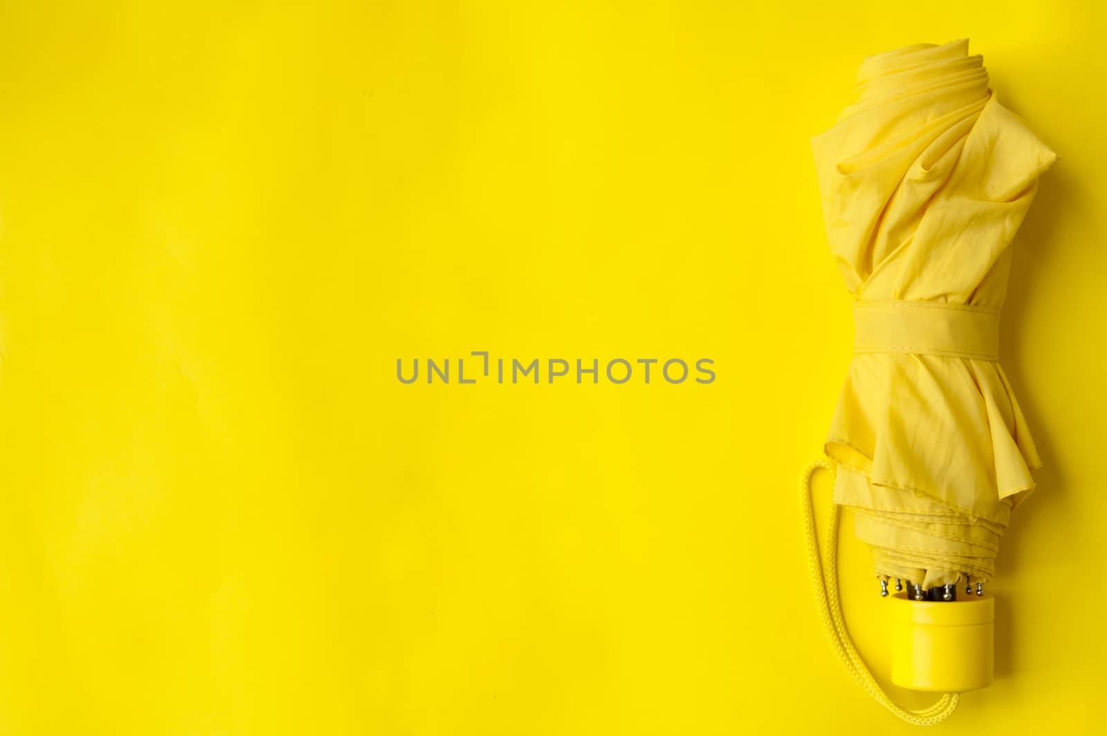 Umbrella on the right side of a yellow background, folded umbrella