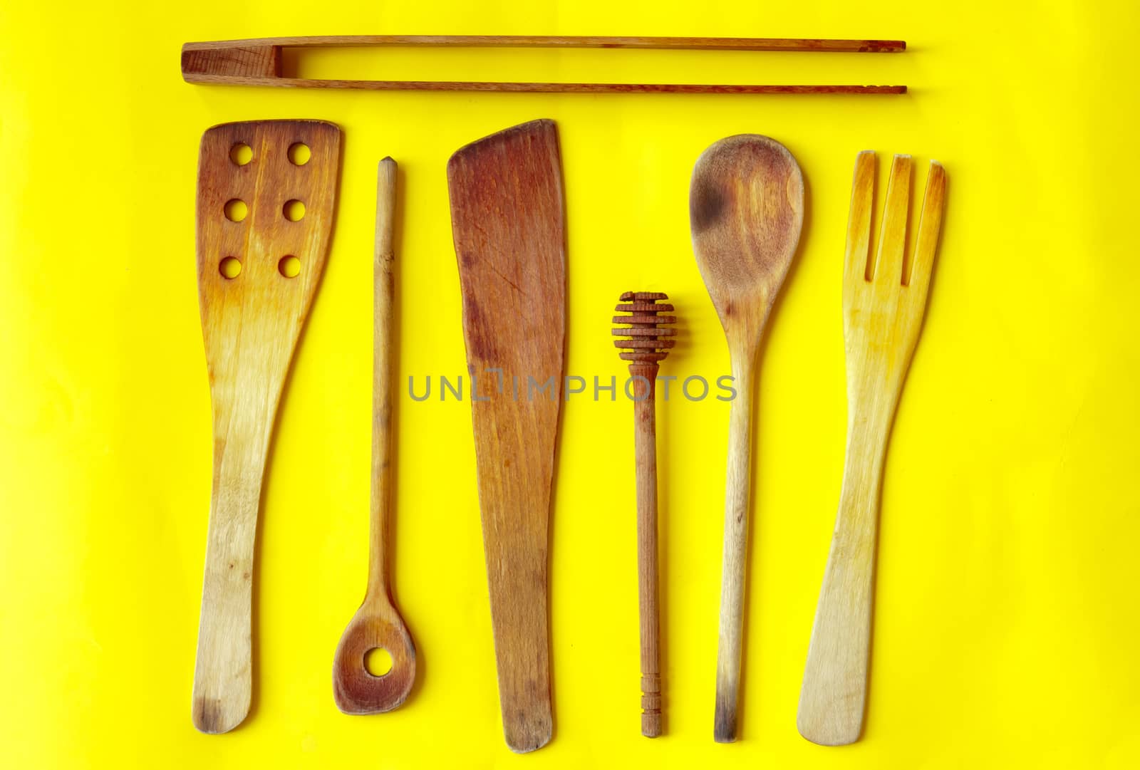 Old wooden spoons and stirrers on yellow background, kitchen utensils