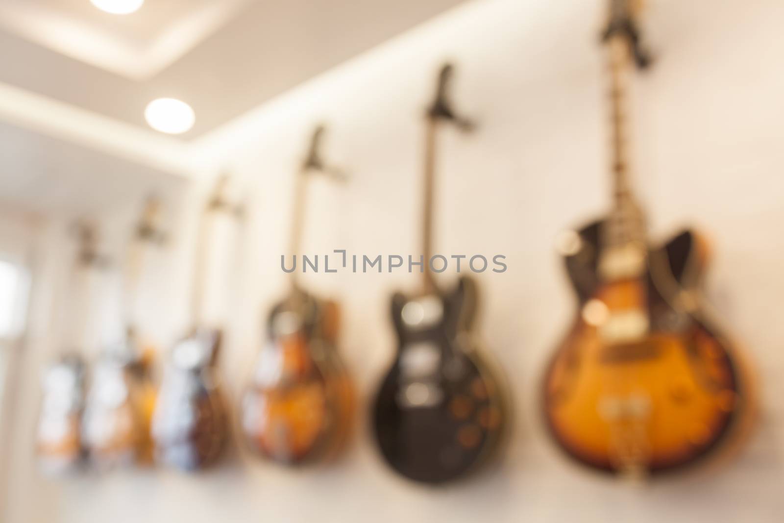 Blur abstract background with guitars hanging on white wall by punsayaporn