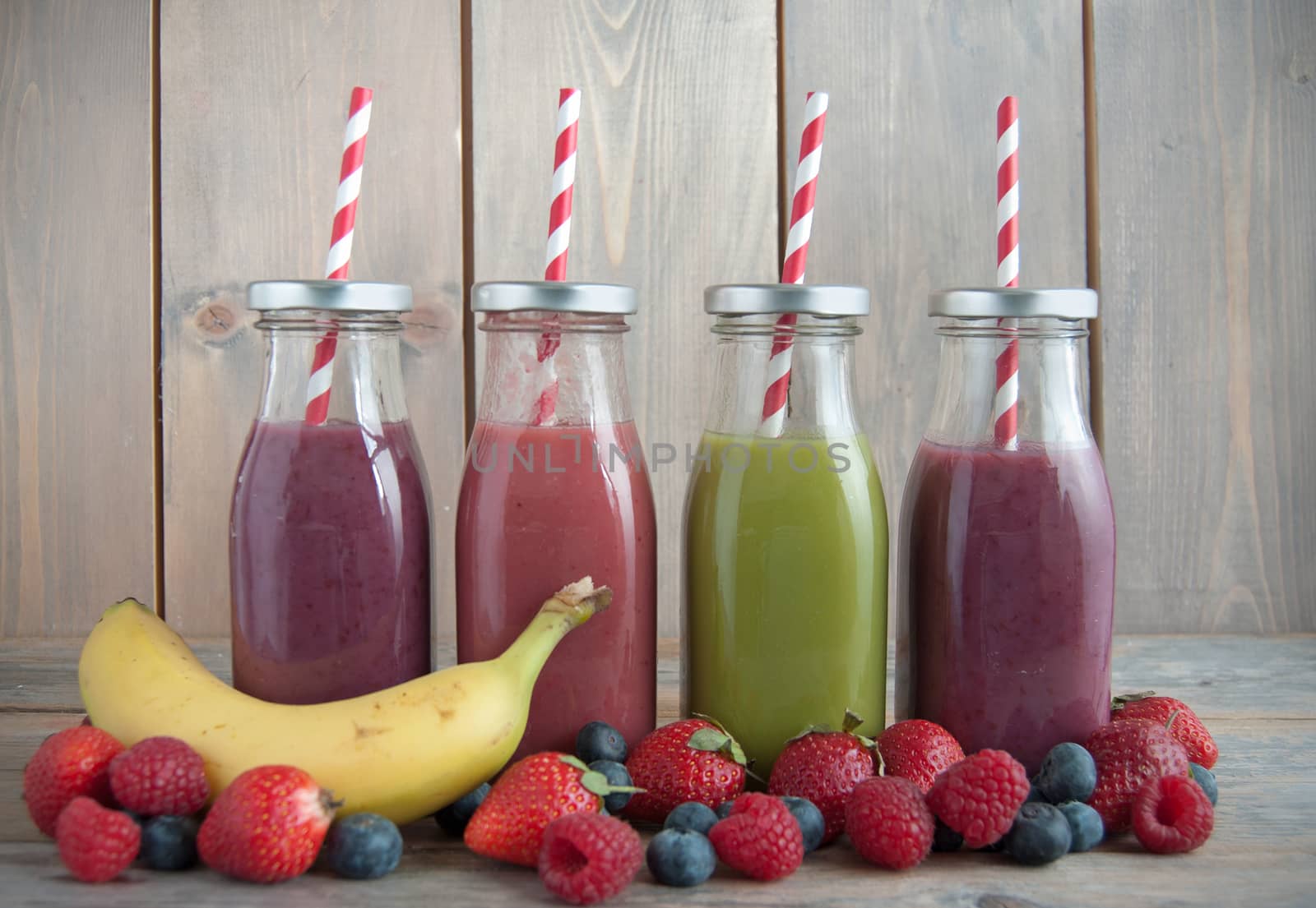 Flavoured smoothies in bottles in a rack over a wooden background