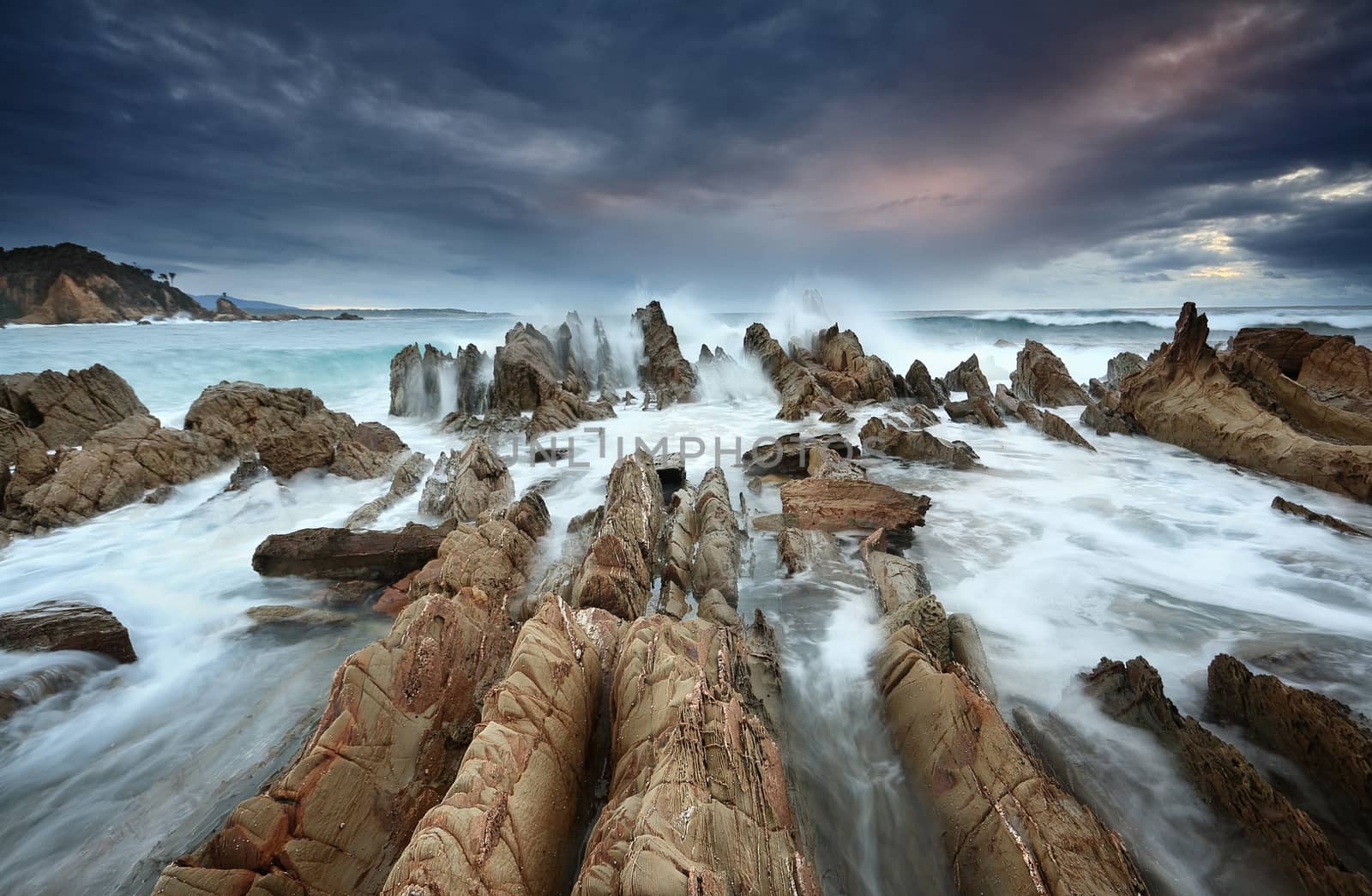 Moody weather,  wild seas, sharp razor and ridge rocks,  big waves wash through constantly.  A glimpse of sunrise highlights some of the cloud temporarily...