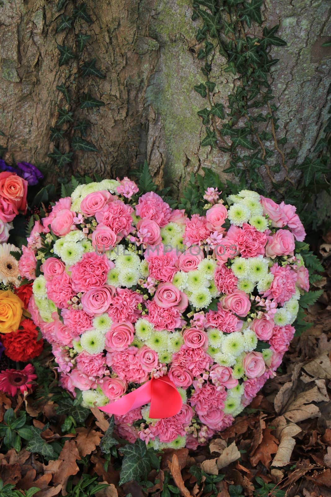 Heart shaped sympathy or funeral flowers near a tree