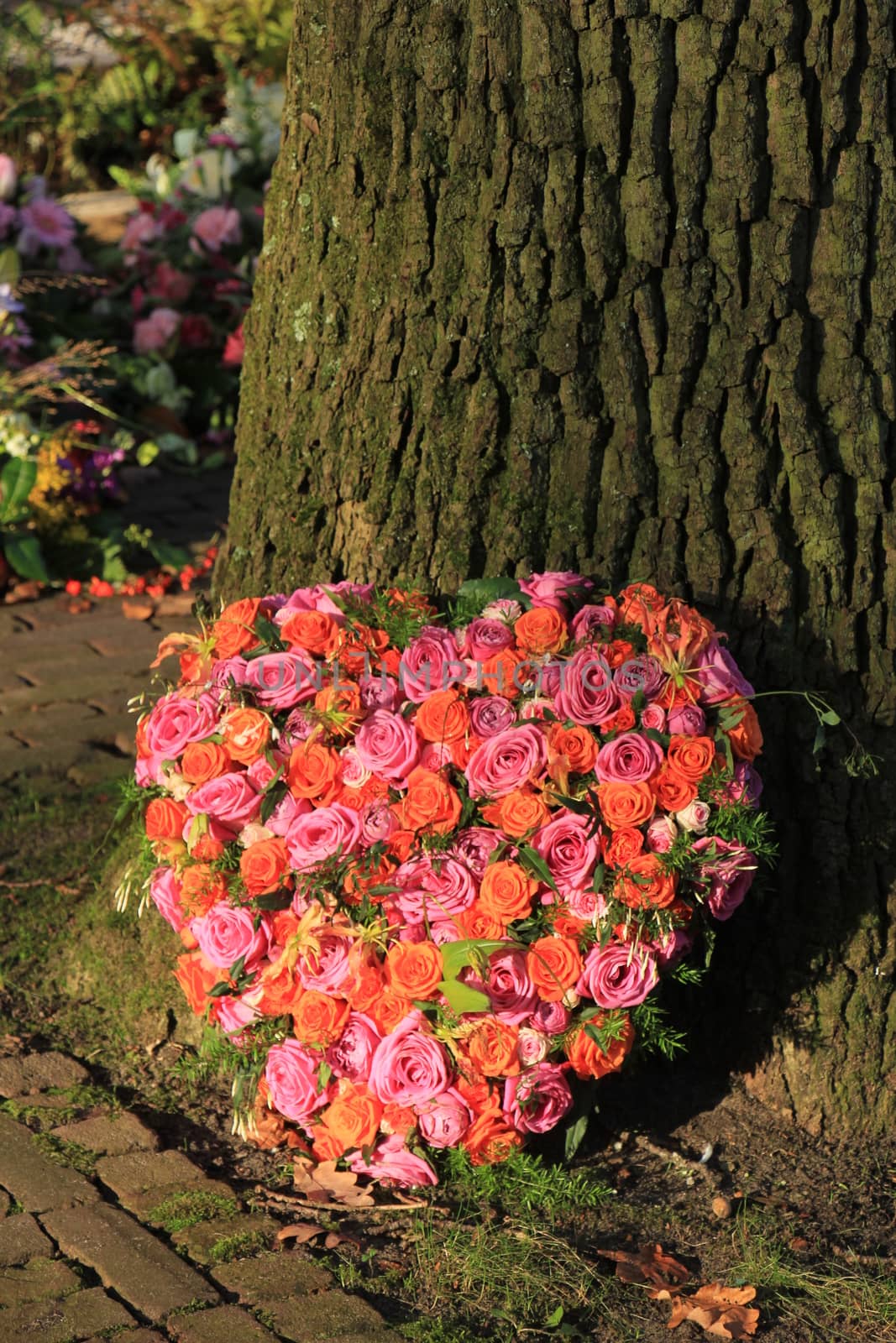 Heart shaped sympathy or funeral flowers near a tree