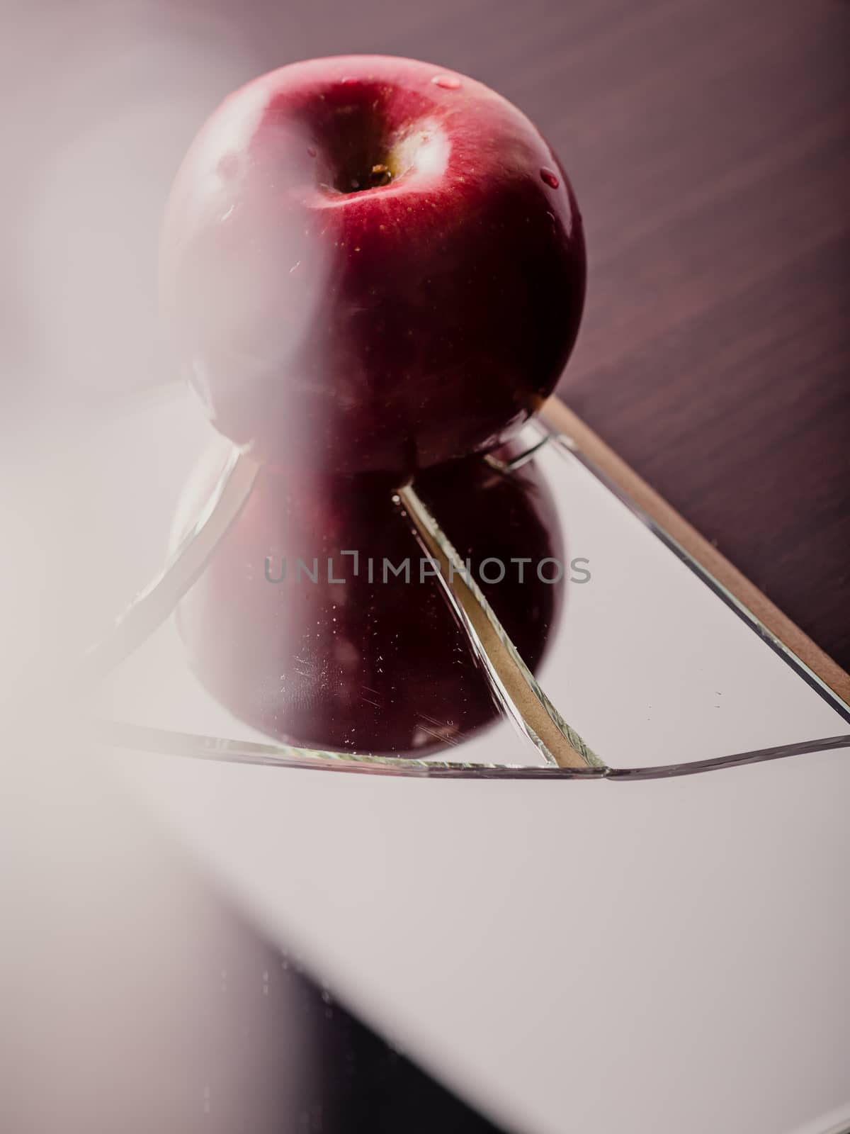 Red apple on cracked broken mirror reflecting