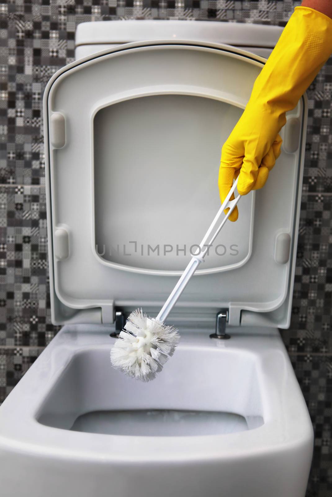 cleaning of white toilet bowl in yellow rubber gloves