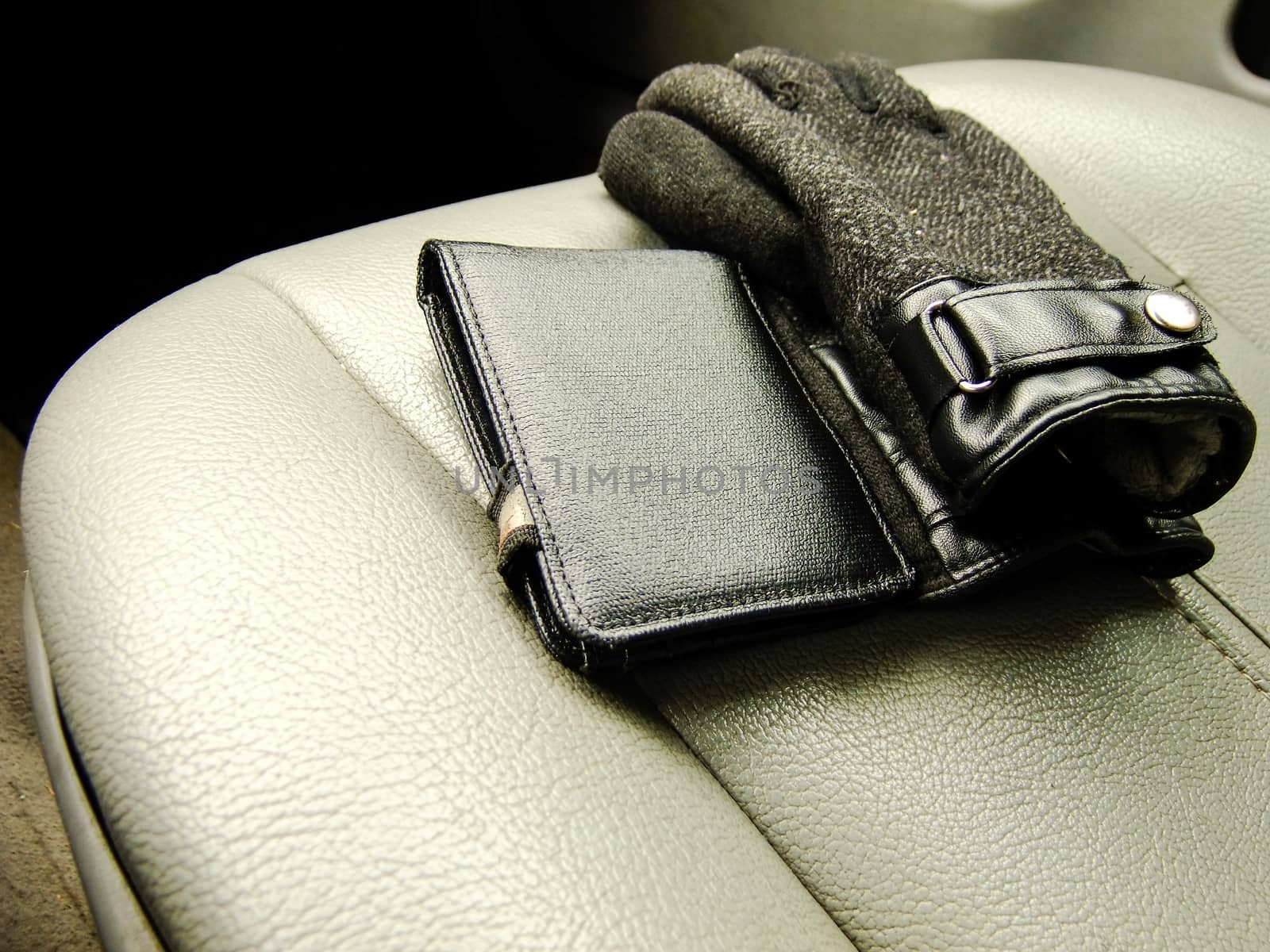 Black Wallet and Mens Gloves on the Background of Front Leather Seat of A luxury Car