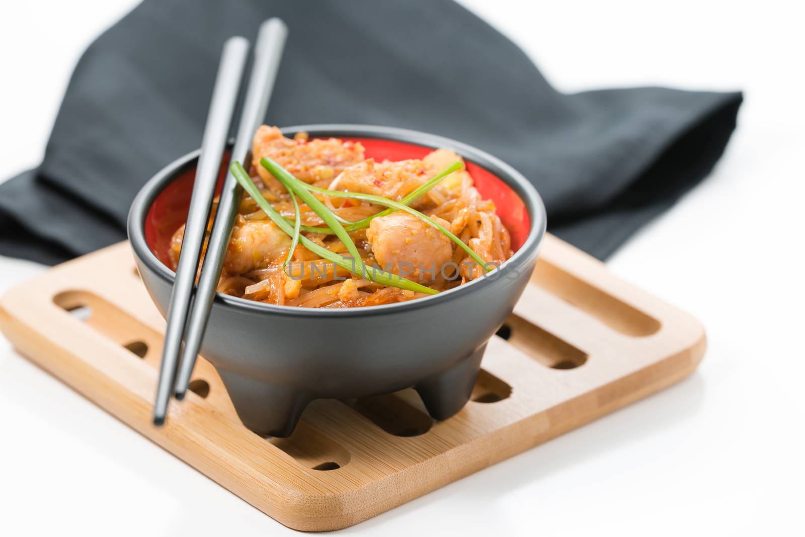 Bowl of delicious chicken pad thai on a bamboo trivet.