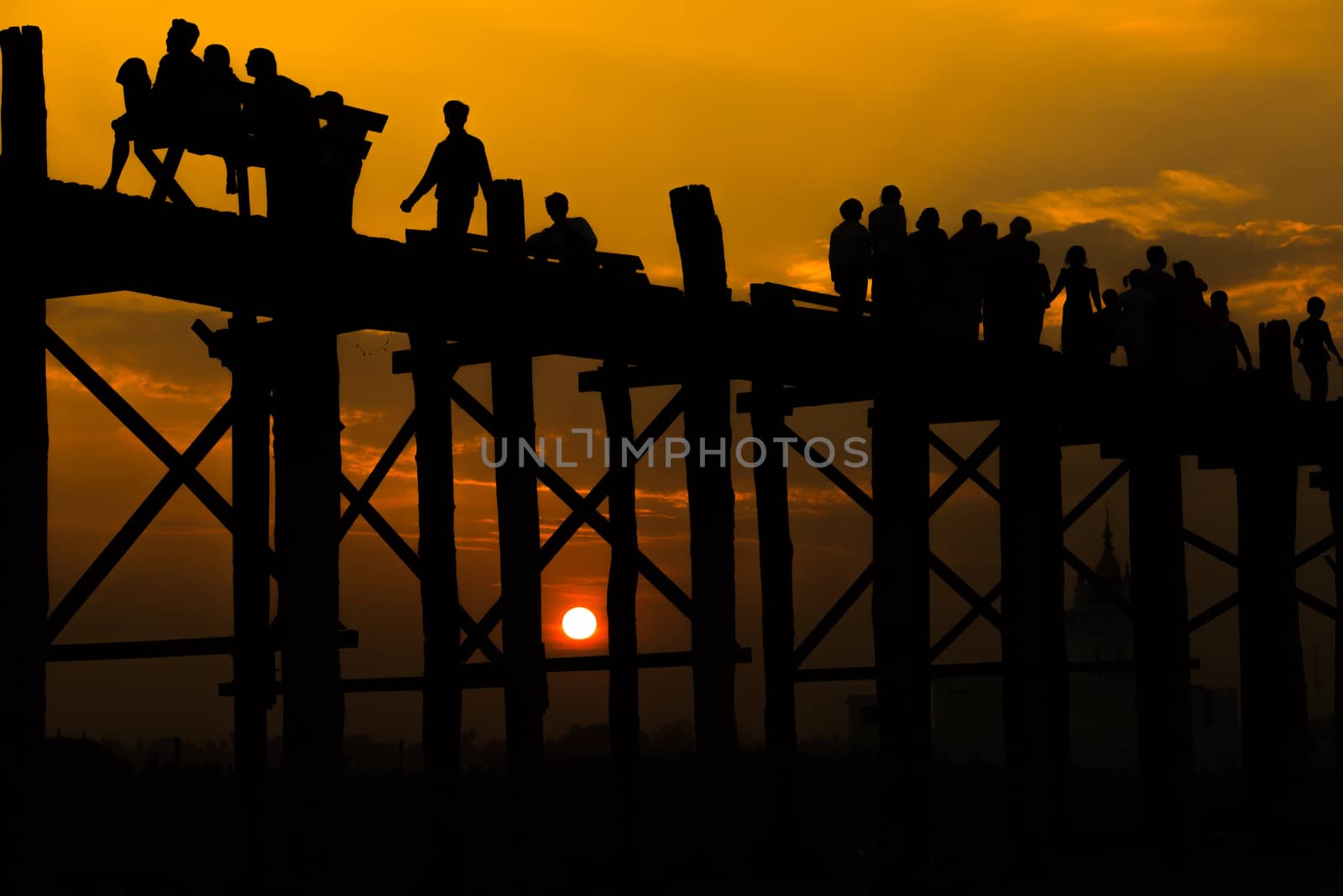 Silhouetted people crossing U bein bridge with sunset,The longest wooden bridge in Mandalay,Myanmar.