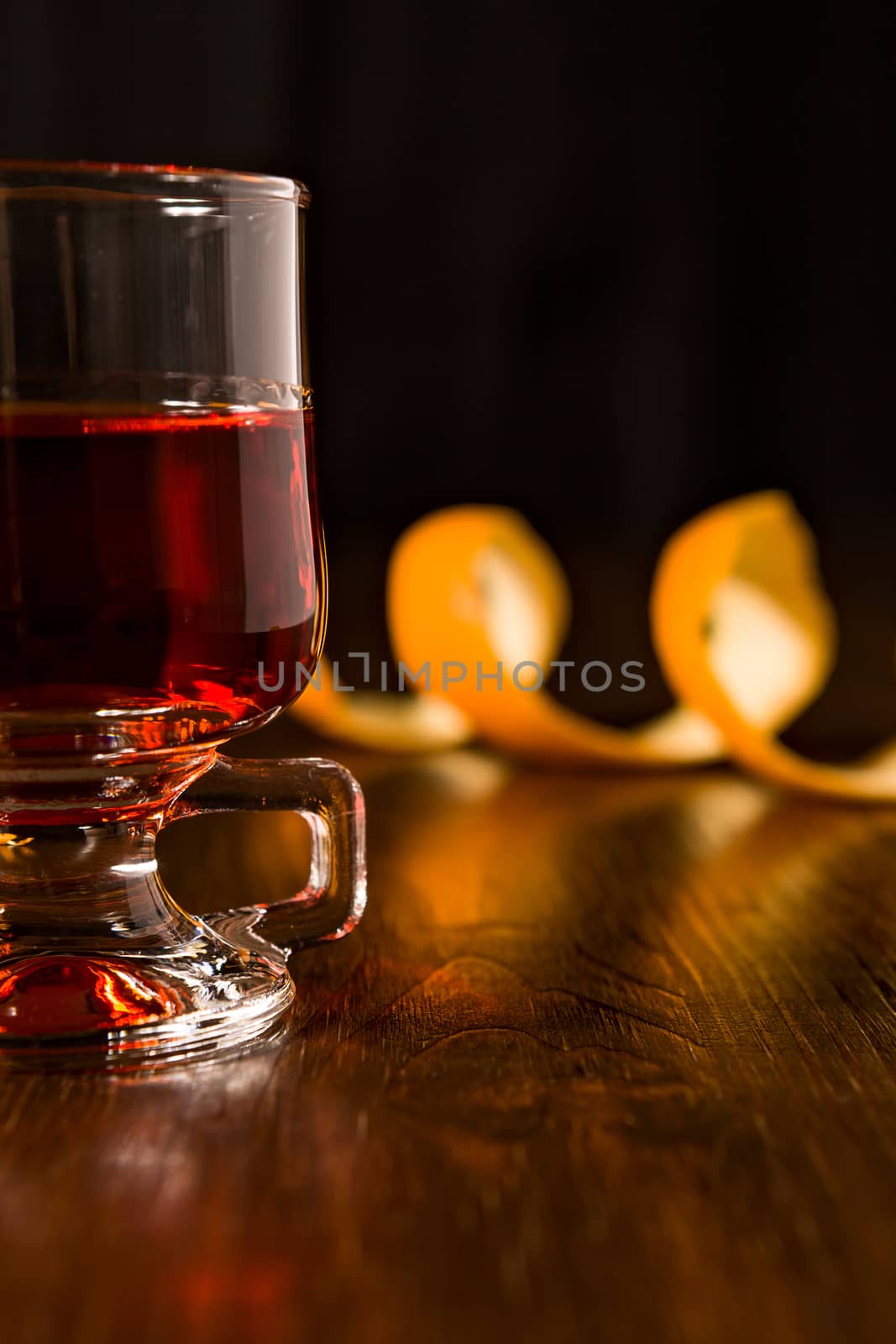 Closeup of alcoholic punch drink and orange peel over a wooden background