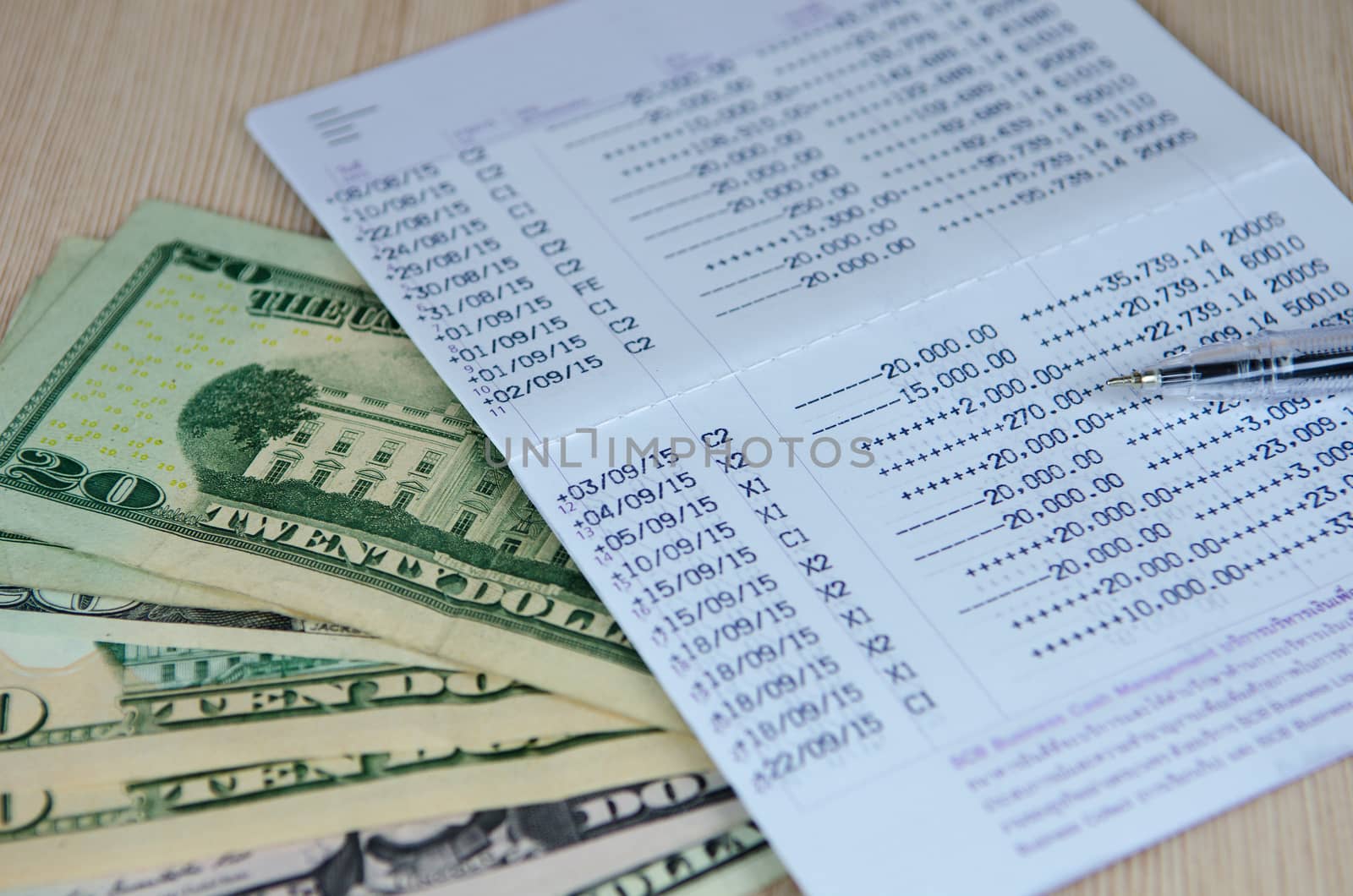 Pen on bank account passbook with dollar banknote, selective focus