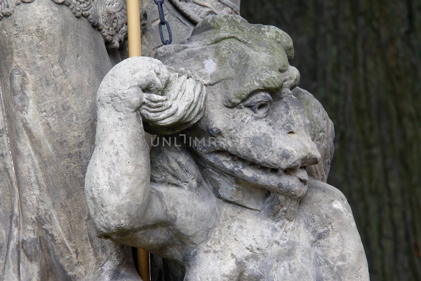 Baroque statue on the crossroad - Saint Procopius with bound devil.
Saint Procopius of Sazava (end of the 10th century Chotoun - March 25, 1053, Sazava) was originally a secular priest, later a hermit, co-founder and first abbot of the monastery Sazava. He was canonized in 1204. 
His main attribute is bound devil, which is at his feet or on which he stands.
Czech republic.