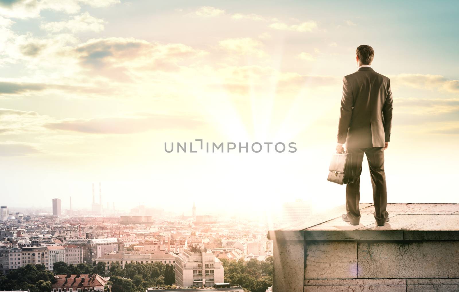 Happy businessman looks sunrise in city, concept for business by cherezoff
