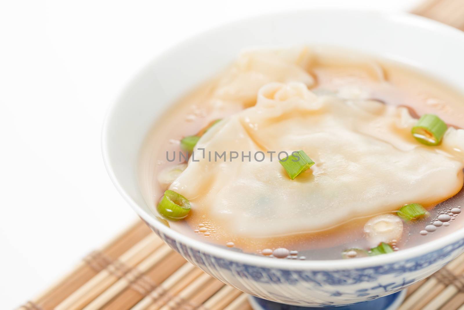 Bowl of wonton soup photographed closeup.  Selective focus to the center of the bowl.