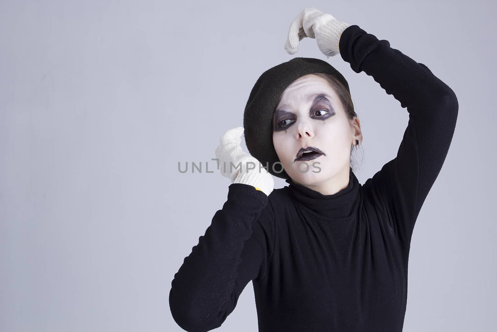 Young woman mime on a background of gray wall