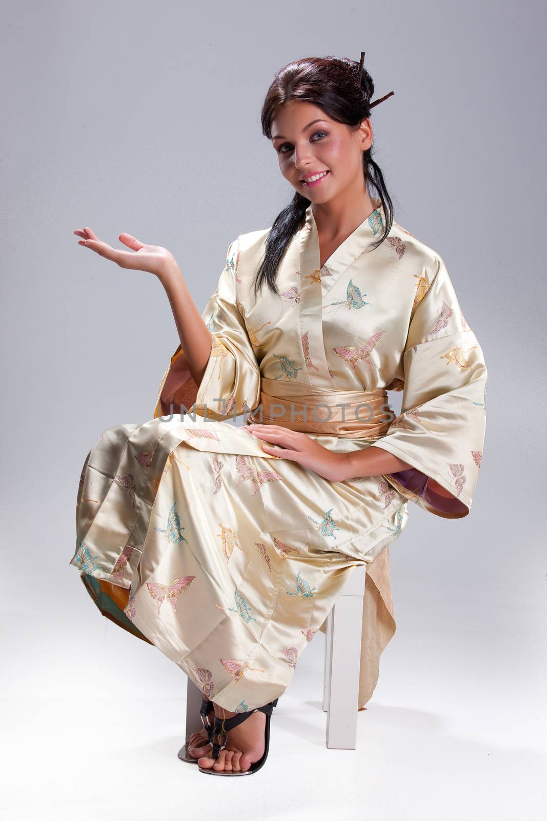Young beautiful woman in japanese national clothing on an isolated studio background