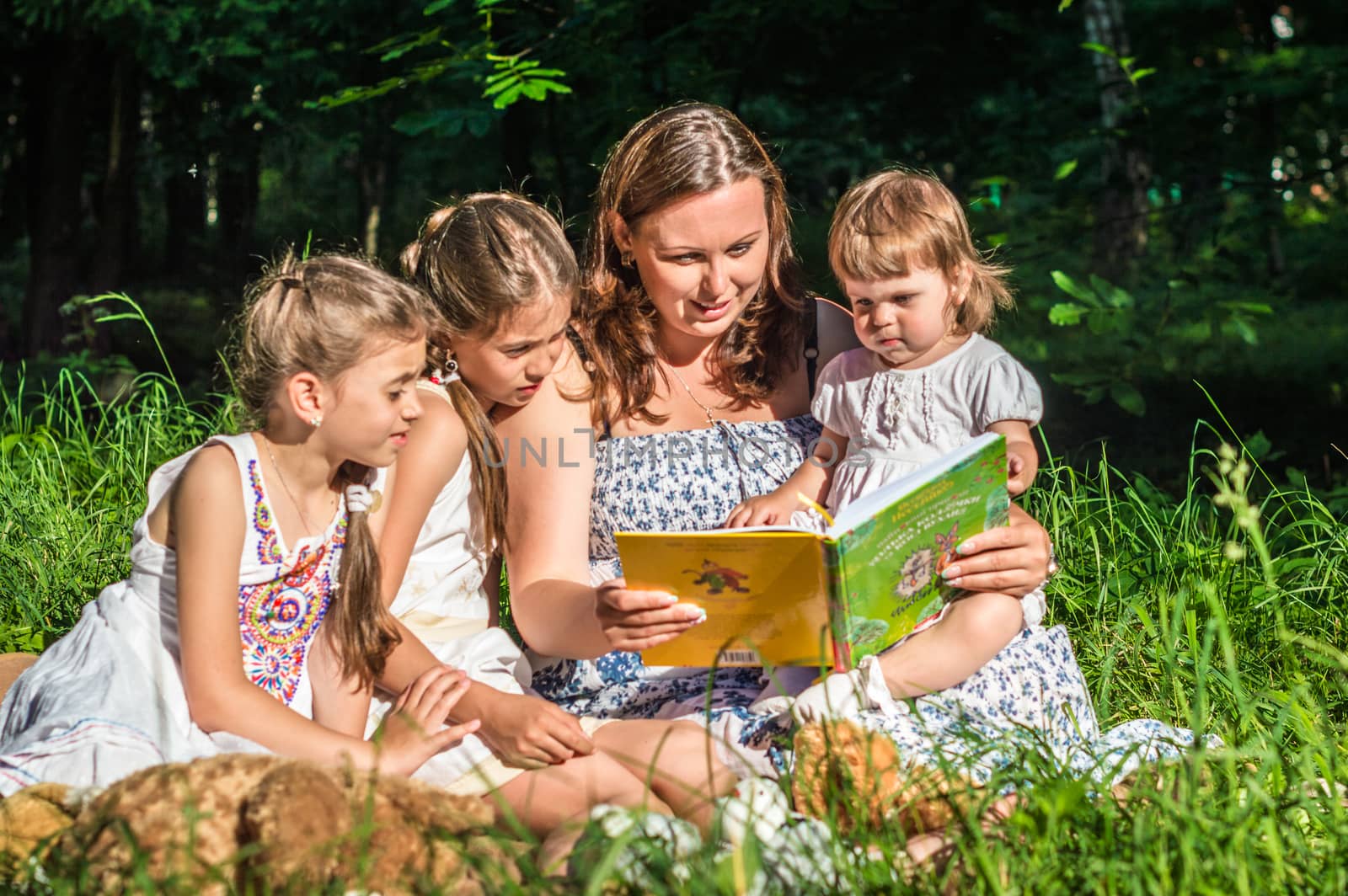 mother reading book with daughters by okskukuruza