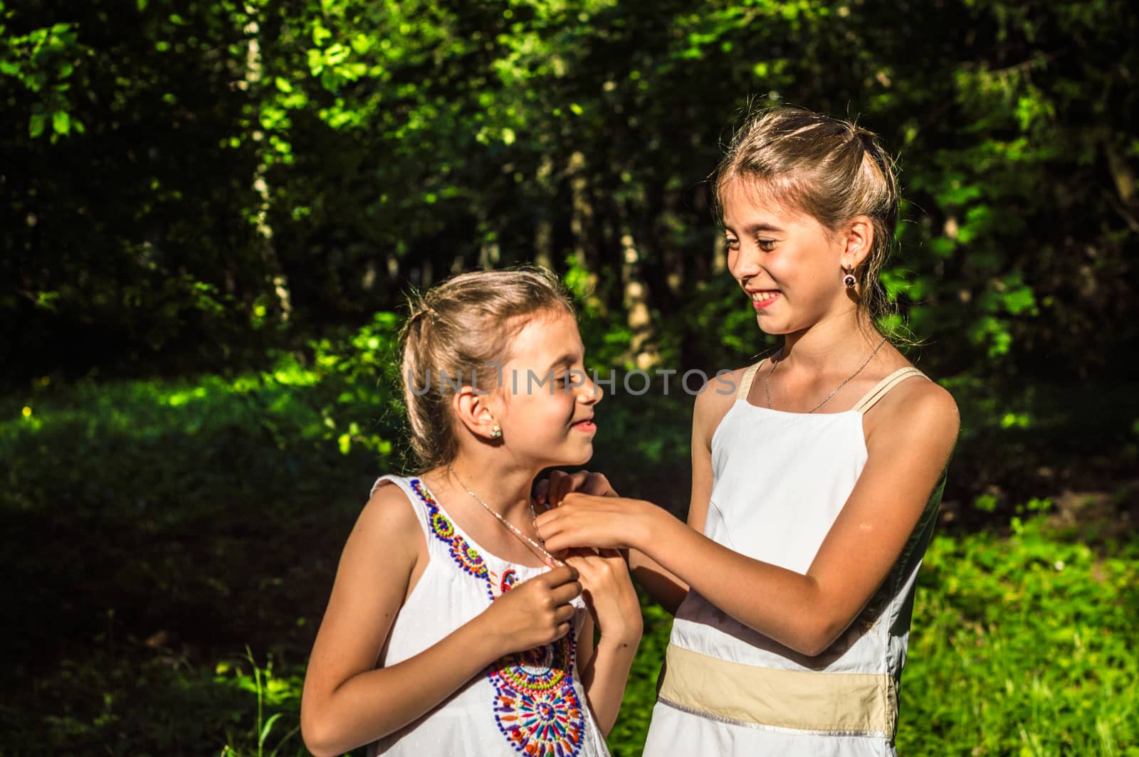 two beautiful daughters hugging and dancing in the park