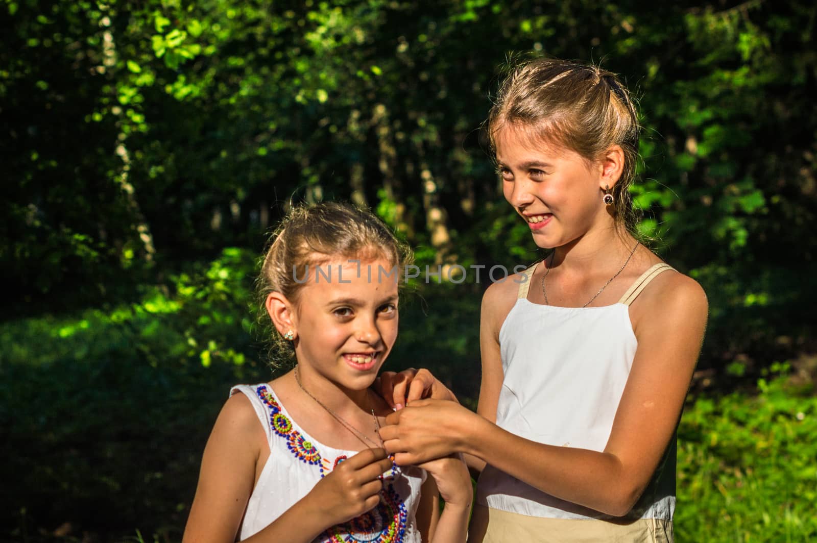 two beautiful daughters hugging and dancing in the park