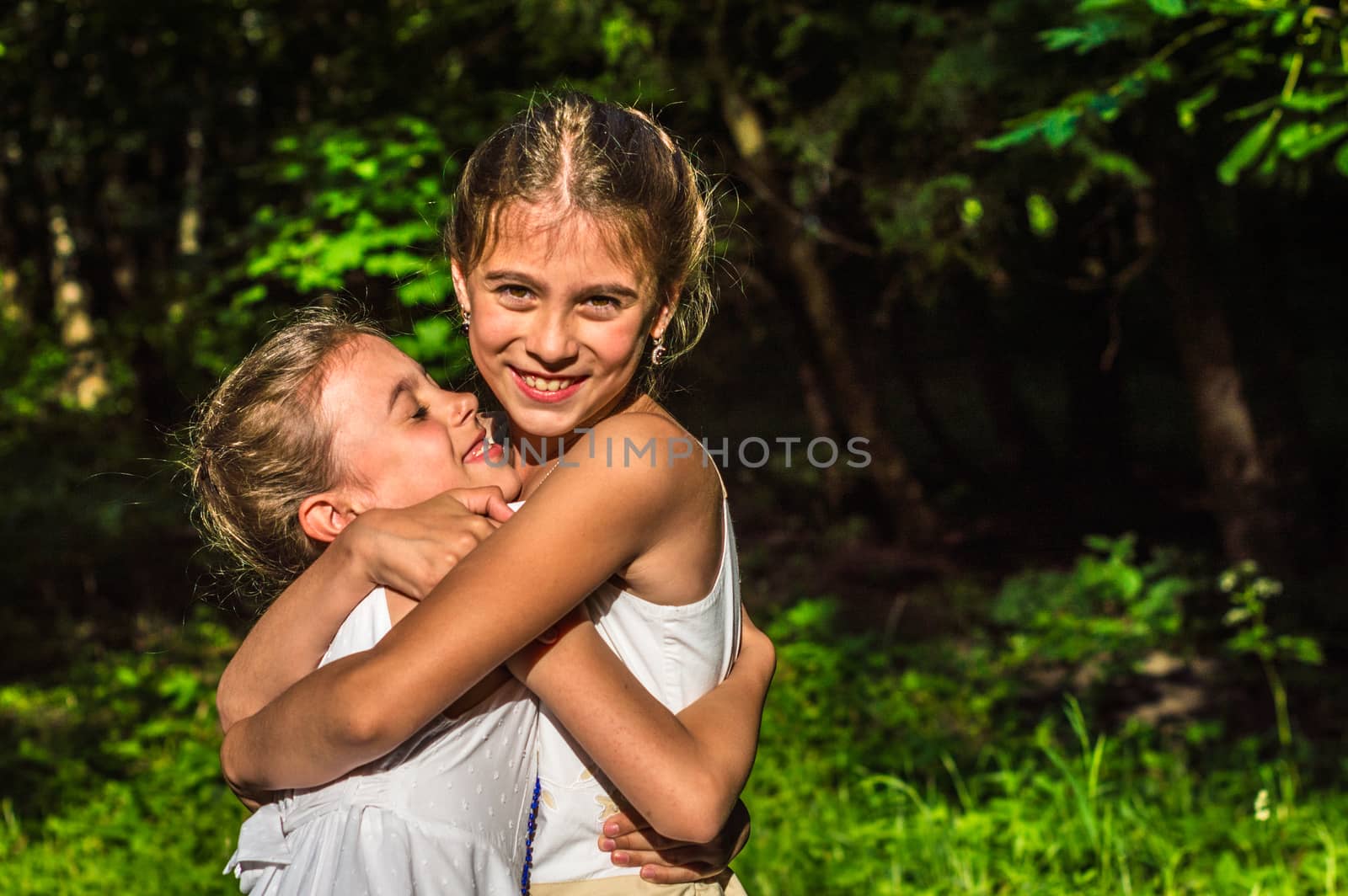 two beautiful daughters hugging and dancing in the park