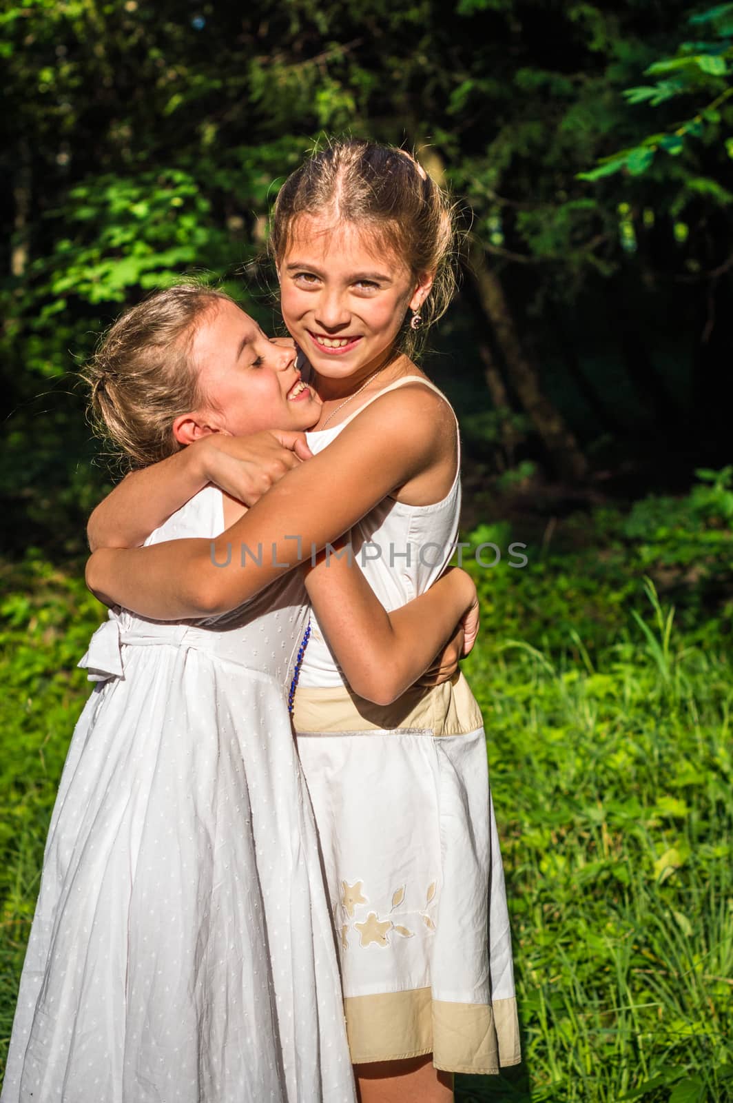 two beautiful daughters hugging and dancing in the park