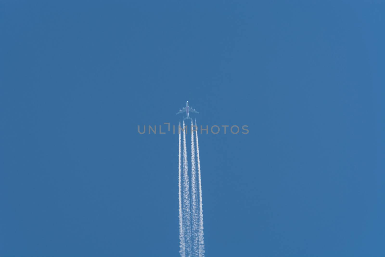 Aircraft flying at high altitude contrails against a dark blue sky.
