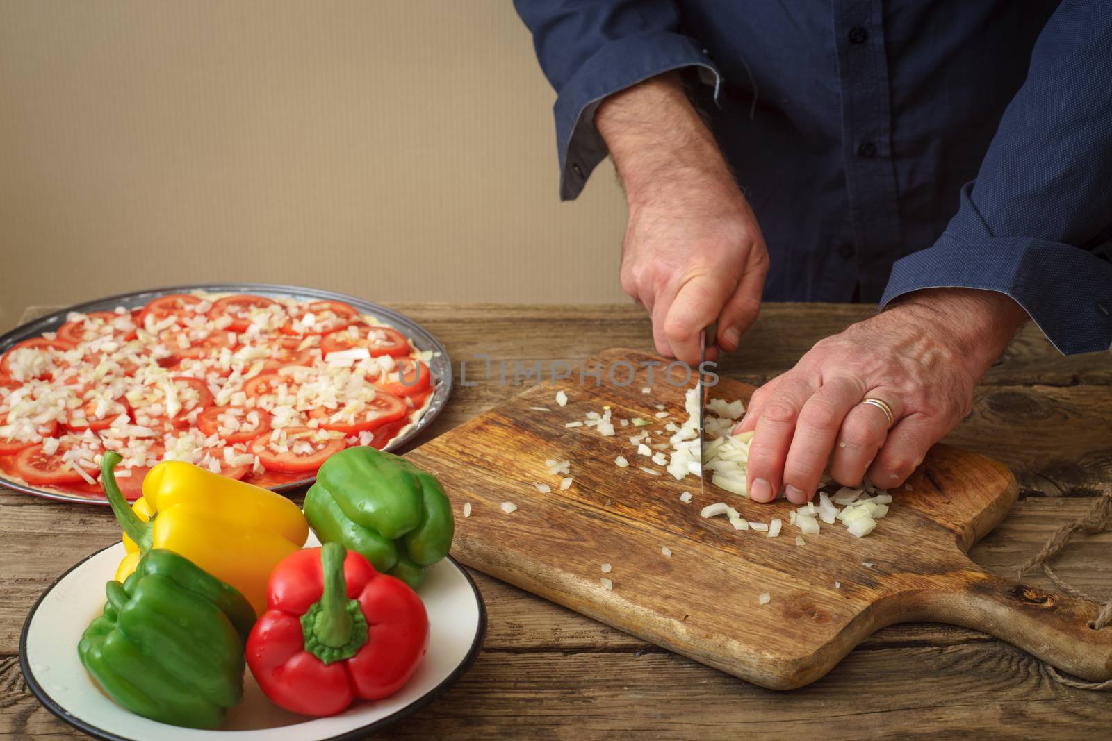 Man knife sliced onion pizza on a wooden board horizontal