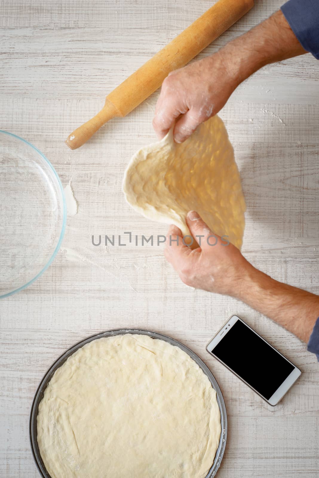 Man cooking dough for two pizzas on the table vertical