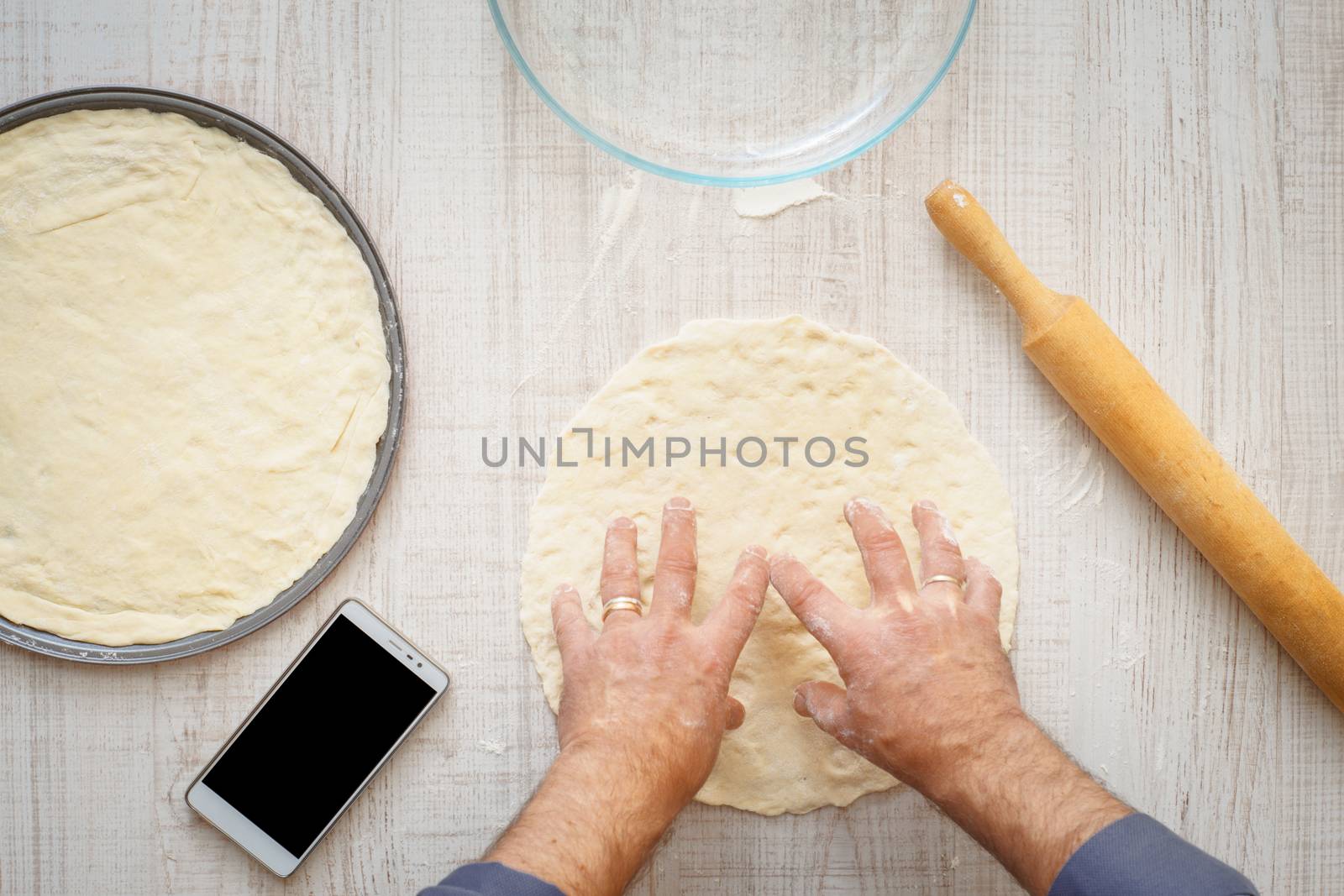 Man cooking dough for two pizzas on the wooden table horizontal