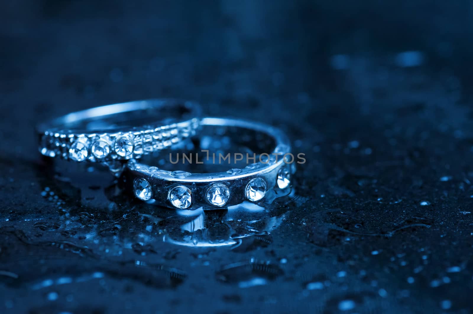 Two rings of white gold on a wet glass table